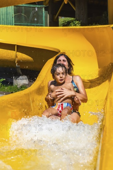 Mother and son enjoying a sunny day at a water park in vancouver, british columbia, sliding down a