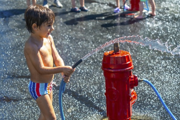 Happy child spraying water with a fire hydrant during a hot summer day in vancouver, british