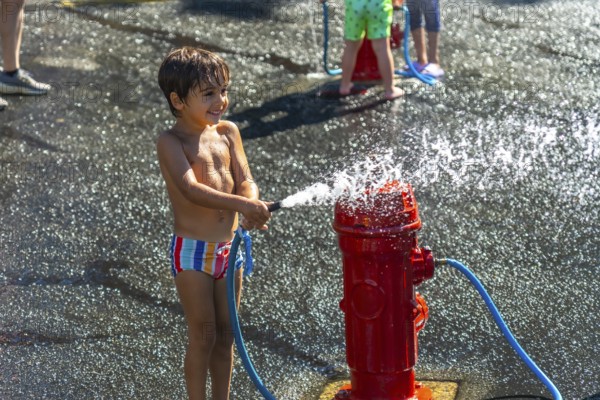 Happy child spraying water from a fire hydrant during a hot summer day in vancouver, british