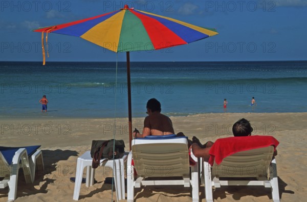 People holding umbrellas and sun loungers on Karon Beach, two years in front of the tsunami, Ko