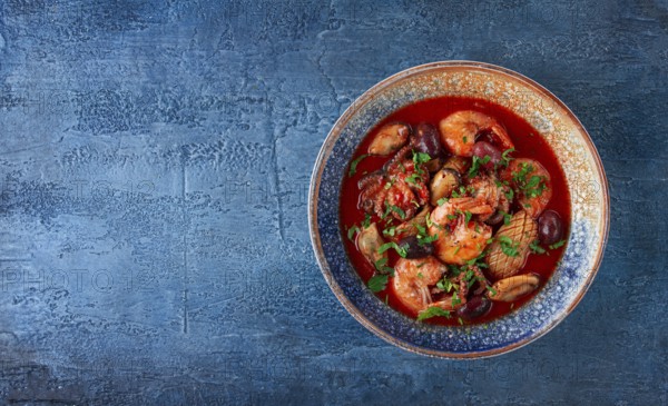 Seafood in tomato sauce with olives, on a dark blue background