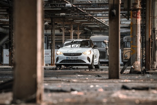 A car is parked in an empty, structured factory building, accentuated by light and shadow, Deer