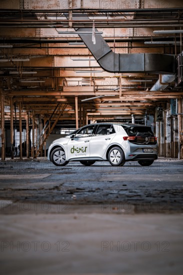 A car in a factory surrounded by structural steel girders and industrial ambiance, Deer E-Car