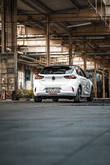 White vehicle in a large, empty industrial building, urban feel, Deer E-Car Sharing, Motorworld