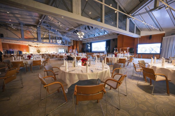 Spacious festively decorated hall with set tables and wide screen, Christmas party Dekra