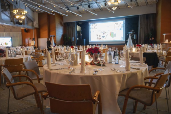 A tastefully furnished room with set tables and a large screen, Christmas party Dekra Congresshotel
