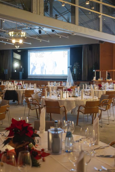Elegant banquet hall with set tables and large screen in a festive atmosphere, Christmas party