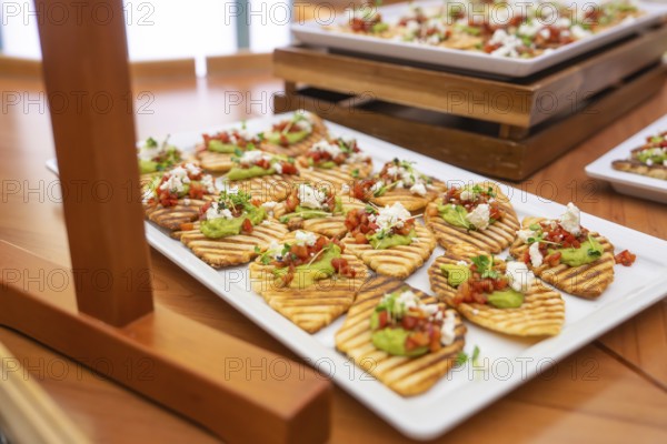 Appetizers with avocado and tomato served appealingly on white plates, Christmas party Dekra