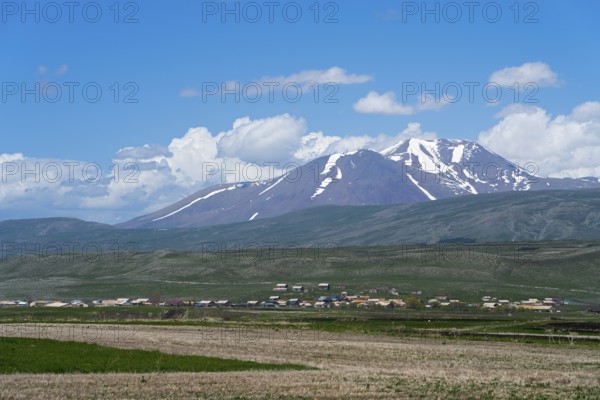 View of snow-capped mountains behind vast fields and a village, landscape near Satche, Mount Didi