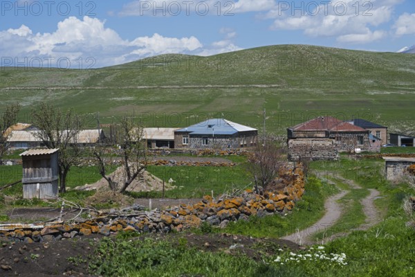 Quiet rural village with stone houses and green fields under blue sky, Jigrasheni,