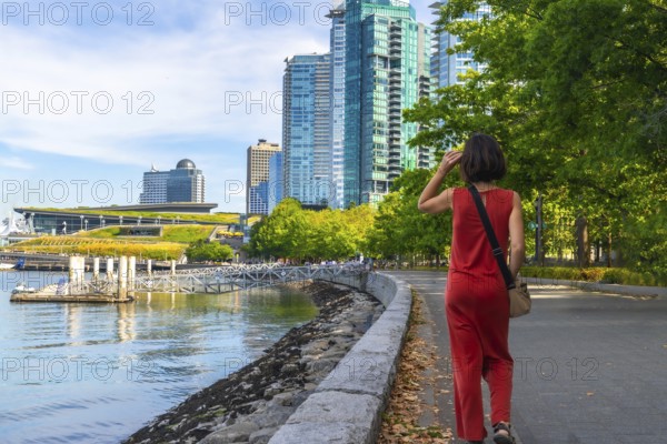 Tourist walking along the scenic seawall in vancouver, enjoying the sunny summer day while
