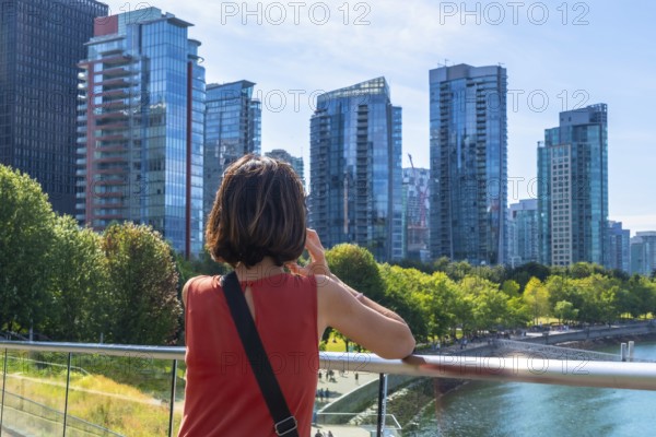 Tourist is making a phone call while enjoying the view of the modern buildings of vancouver's