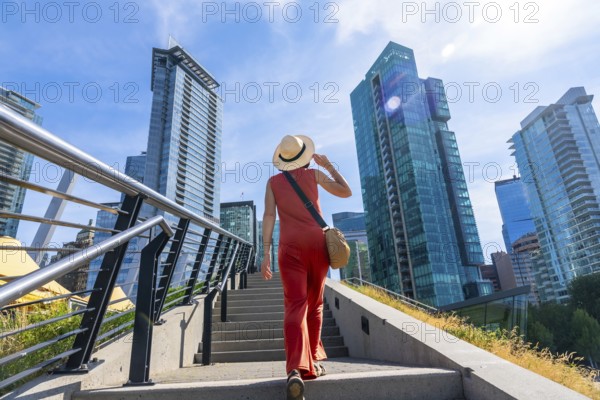 Tourist wearing a straw hat walking up stairs in vancouver, british columbia, canada with modern