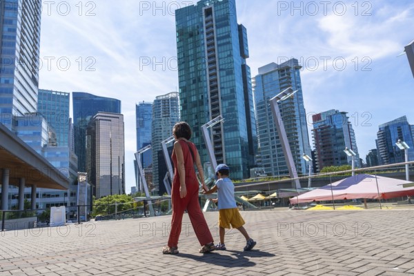 Mother and son holding hands walking in downtown vancouver, british columbia, canada, enjoying a