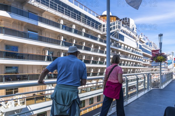 Two tourists are enjoying the view of a large cruise ship docked at canada place in vancouver,