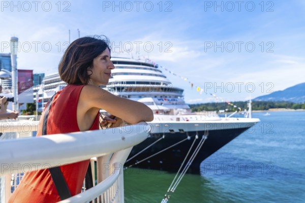 Tourist leaning on railing, admiring large cruise ship docked in harbor of vancouver, british