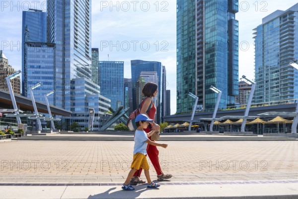 Mother and son enjoying a leisurely stroll through a modern urban square, surrounded by the