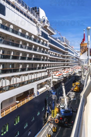 Large cruise ship docking in vancouver, british columbia, with lifeboats hanging from the side and
