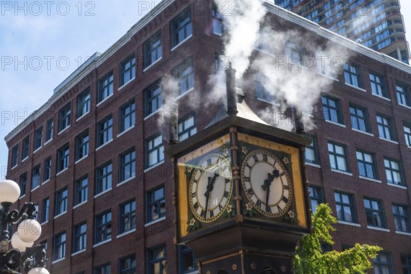 Steam clock releasing vapor against a backdrop of a red brick building and a bright blue sky,