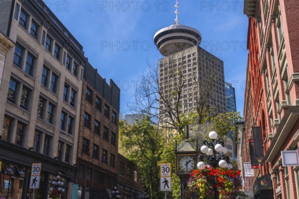 Gastown steam clock with flower decorations rising towards harbour centre, a skyscraper located in