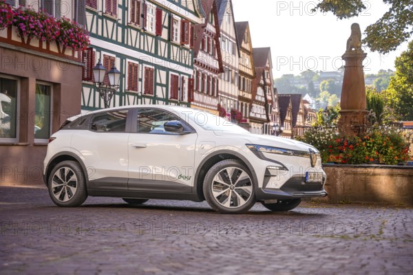 Side view of white car in a historic town with half-timbered houses in summer, Deer e-car sharing,