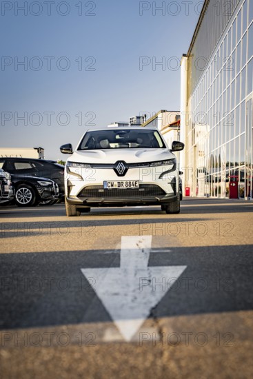 A modern white car is parked in a parking lot in front of a glass front, Deer E-Carsharing, Renault