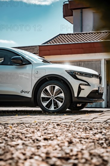 White electric car standing on paved ground in front of a modern house, Deer e-Carsharing, Renault