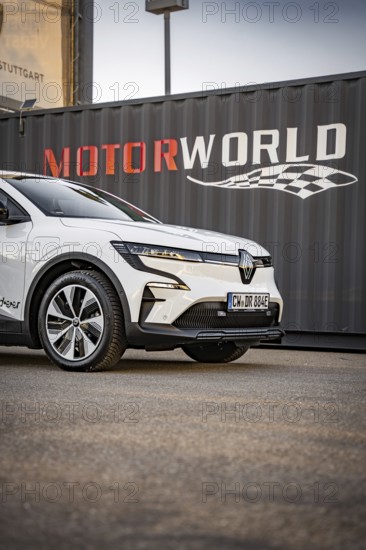 Close-up of a white electric car in front of a container with Motorworld logo, Deer E-Carsharing,