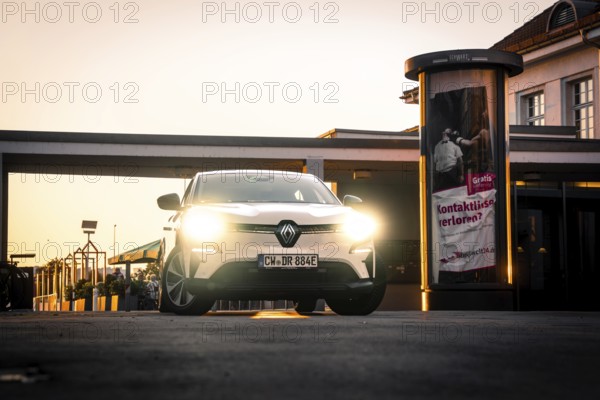 Car with lights switched on stands in front of illuminated lanterns and advertising banners, Deer