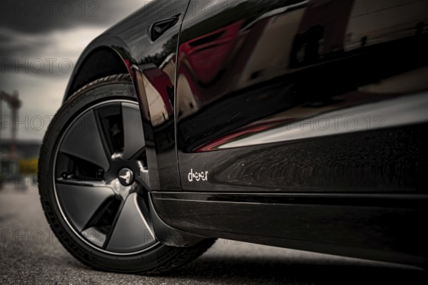Side view of a black car with emphasis on the rims and tires, Deer E-Carsharing, Tesla Model 3,