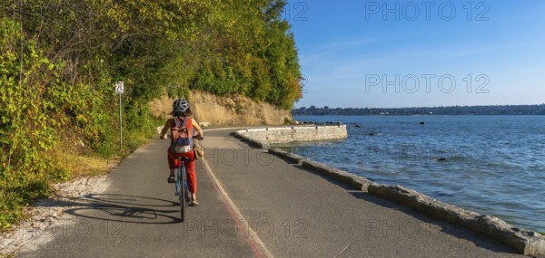 Tourist cycling through stanley park, soaking in stunning ocean views and vibrant cityscapes of