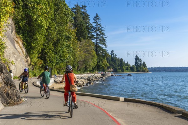 Tourists are cycling on the seawall in stanley park, enjoying the scenic views of the ocean and