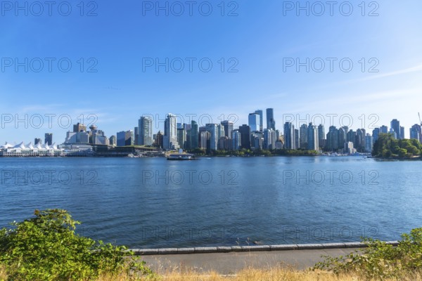 Panoramic view of vancouver's modern skyline rising above the calm pacific ocean on a sunny day,