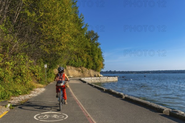 Tourist cycling through stanley park, soaking in stunning ocean views and vibrant cityscapes on a