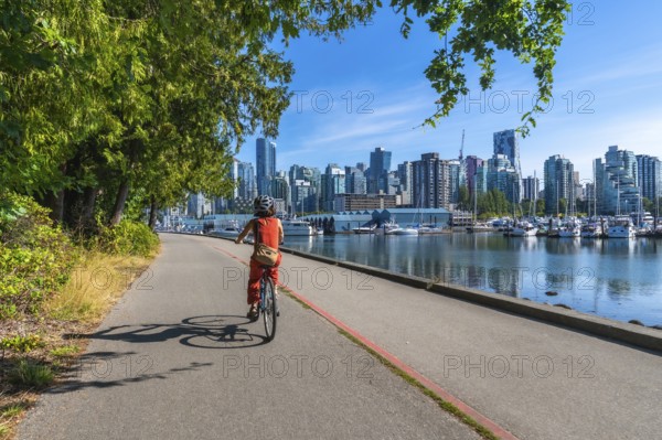 Tourist riding bicycle on the seawall in stanley park enjoying the scenic view of the vancouver
