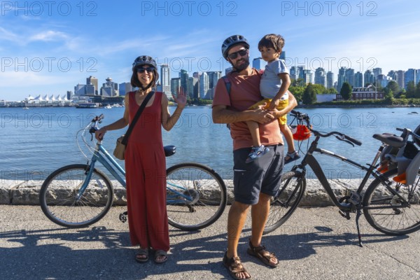 Happy family with bicycles enjoying a sunny day by the sea, taking a break from their ride with the