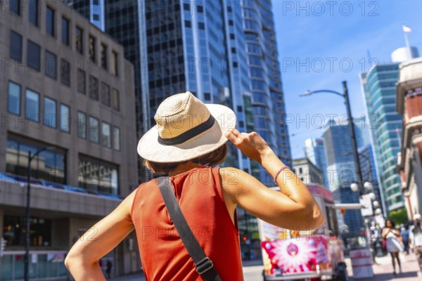 Young woman tourist holding her straw hat is admiring the skyline of vancouver downtown in british