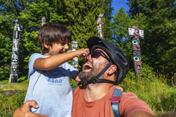 Playful father and son are enjoying a sunny day at brockton point in stanley park, vancouver,