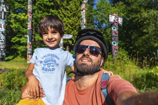 Father and son enjoying a sunny day at brockton point in stanley park, vancouver, taking a selfie