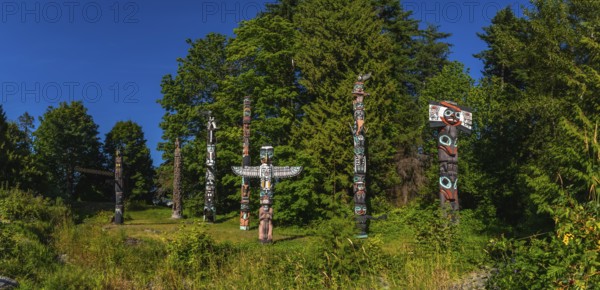 Totem poles rising against a backdrop of lush greenery and blue sky, reflecting the rich history