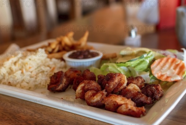 Breaded shrimp with rice and salad served on wooden table. Close up of breaded shrimp with french