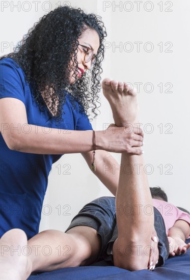 Physiotherapist with patient performing knee flexion, Smiling physiotherapist performing knee