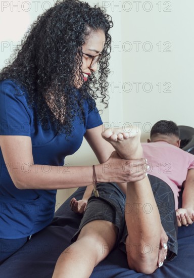 Smiling physiotherapist performing knee flexion physiotherapy, Physiotherapist with patient