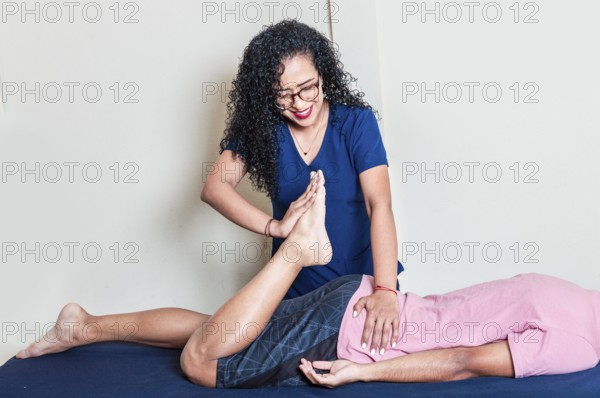 Smiling physiotherapist giving massage to lying patient. Female physiotherapist practicing lumbar