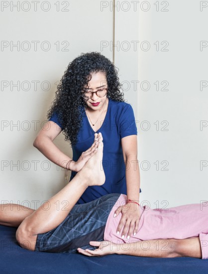 Young woman physiotherapist with lying patient. Physiotherapy rehabilitation concept, Lumbar