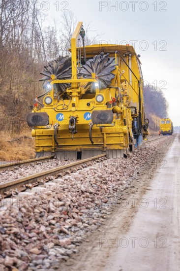 Yellow track construction machine on a railroad track in use on a construction site, tamping