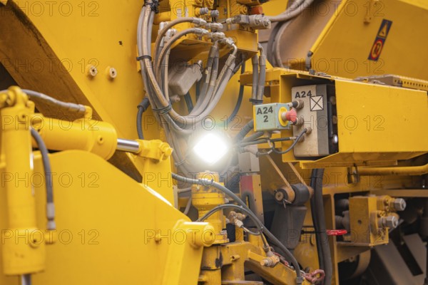 Close-up of yellow machine parts with cables and technical details, tamping machine on Hermann,