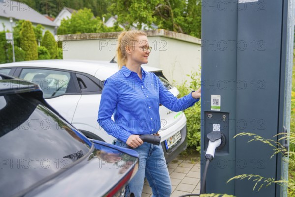 Woman uses charging station for electric cars in a municipal parking lot, Deer e-Carsharing, Calw,