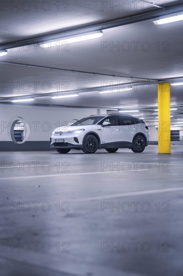 White car in empty underground garage with yellow pillar and neon light atmosphere, deer e-car