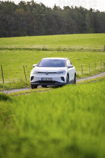 SUV on a path between vast green fields, deer e-car sharing, VW ID4, Calw, Germany